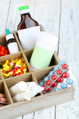 Medical pills, ampules in wooden box, on color background