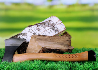 Ax and firewood on green grass, on nature background