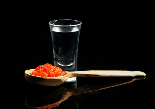 Glass of vodka, red caviar  isolated on black