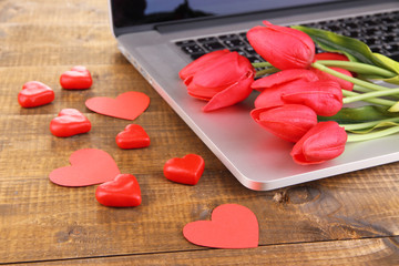 Computer with red hearts and flowers on table close up