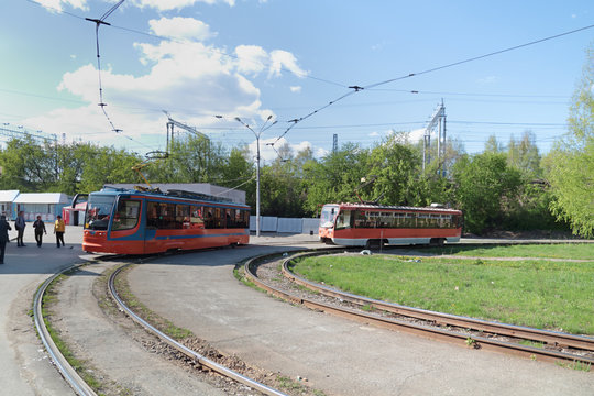 Two orange trams unfold at terminus in city at sunny summer day