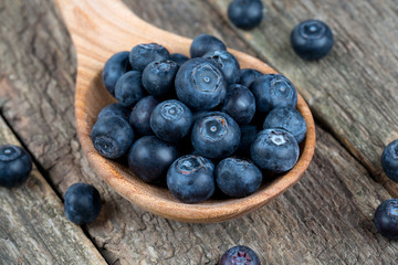 fresh blueberries in a wooden spoon over wooden table