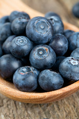fresh blueberries in a wooden spoon over wooden table