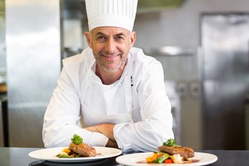 Confident male chef with cooked food in kitchen