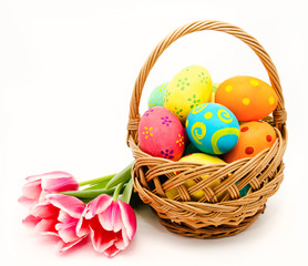 Colorful easter eggs in basket and flowers isolated on a white