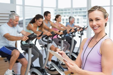 Fototapeta premium Trainer with people working out at spinning class