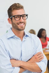 Fototapeta premium Attractive designer smiling at camera with colleagues behind him