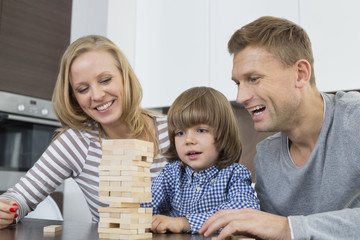 Happy parents and son playing with wooden blocks at home