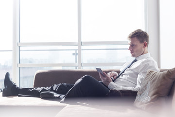 Full length of businessman using digital tablet on sofa at home