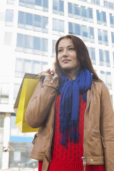 Thoughtful woman carrying shopping bags in winter