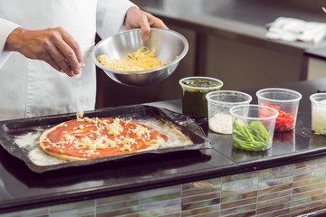 Mid section of a chef garnishing food in kitchen