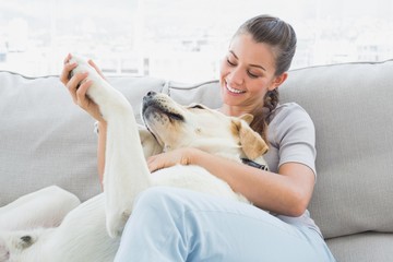 Happy woman petting her yellow labrador on the couch