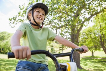 Obraz premium Smiling young boy riding bicycle at park