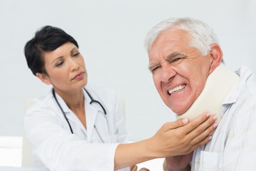 Fototapeta premium Female doctor examining a senior patients neck