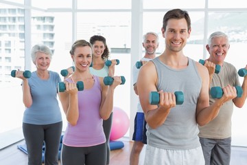 Class exercising with dumbbells in gym