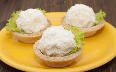 Tartlets with cheese and egg balls on a yellow plate   .