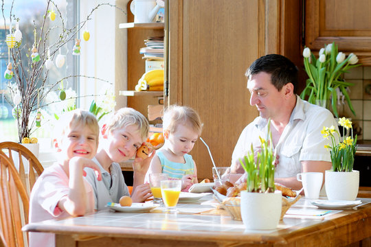 Father With Kids Eating Eggs During Family Breakfast On Easter