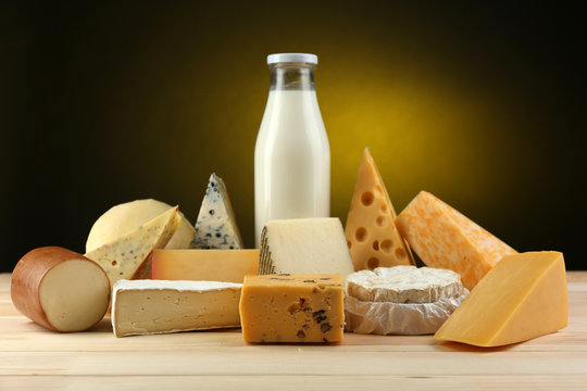 Tasty dairy products on wooden table, on dark background