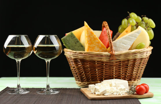 Basket with different cheese and glasses of wine