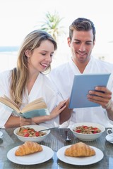 Obraz na płótnie Canvas Couple with book and digital tablet on breakfast table