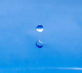 a drop of water falling in blue water. macro