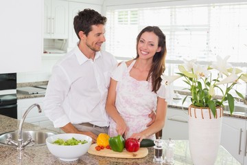 Portrait of happy couple cutting vegetables in kitchen