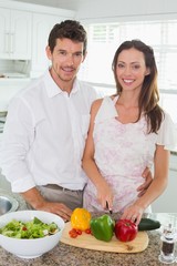 Portrait of a couple cutting vegetables in kitchen