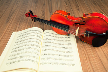 Vintage violin and sheet music in wood background