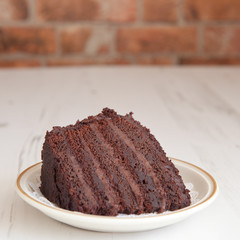 A piece of chocolaste fudge cake on a brick wall background, sel