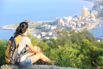 Fototapeta na wymiar woman hiker sit on seaside mountain peak enjoy the view