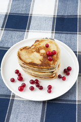 Heart shaped pancakes with cranberries on porcelain plate. Close