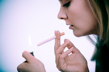 Young woman with lighter lighting up cigarette. Girl smoking.