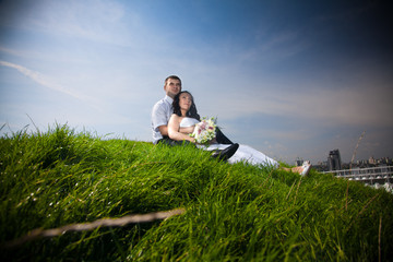 Newly married couple sitting on top of hill and looking at sky