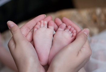Women's hands holding baby feet