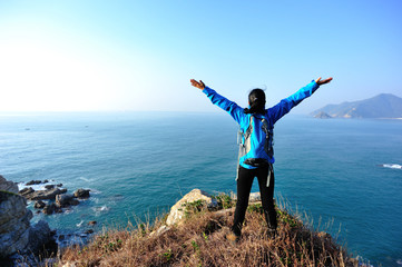 cheering woman hiker seaside mountain peak