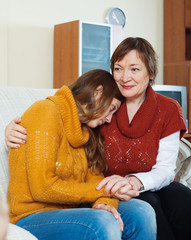 Mature mother comforting crying adult daughter
