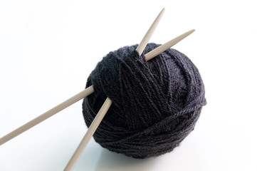 Ovillo de lana negra con dos agujas de tejer