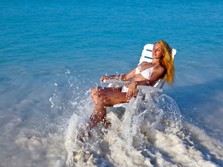 Young pretty woman in a beach chair at ocean..