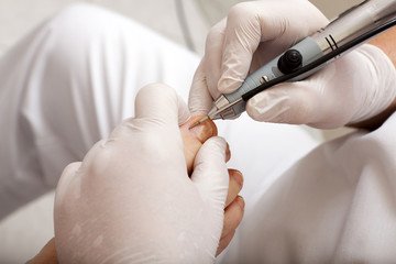 Fußpfleger mit einer Schleifmaschine am arbeiten