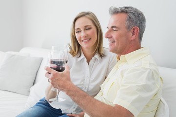 Obraz premium Relaxed couple with wine glasses sitting on sofa