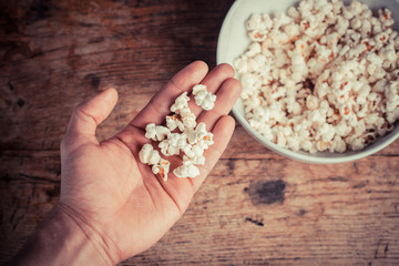 Hand getting popcorn from bowl