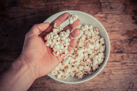 Hand getting popcorn from bowl