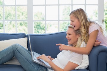 Obraz premium Girl pointing at laptop while mother using it