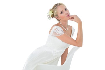 Fototapeta na wymiar Confident bride with hand on chin leaning on chair