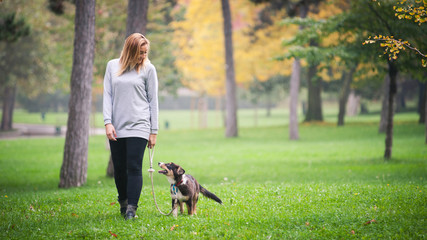 Young woman walking with Australian Shepherd dog outdoors in the - 62255314