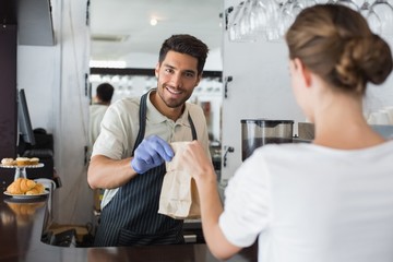 Fototapeta premium Waiter giving packed food to a woman at coffee shop