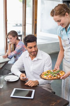 Waitress giving pizza to a man at coffee shop