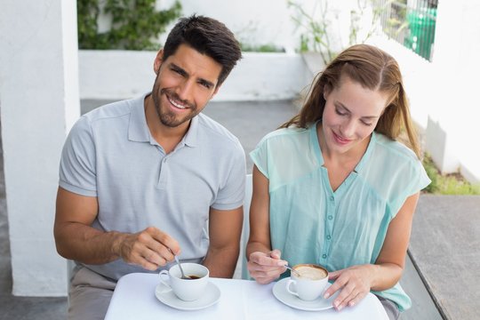 Smiling couple with coffee cups at café