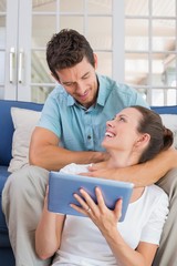 Fototapeta premium Happy couple using digital tablet on couch