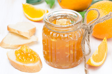 Obraz na płótnie Canvas orange jam in a glass jar and fresh bread